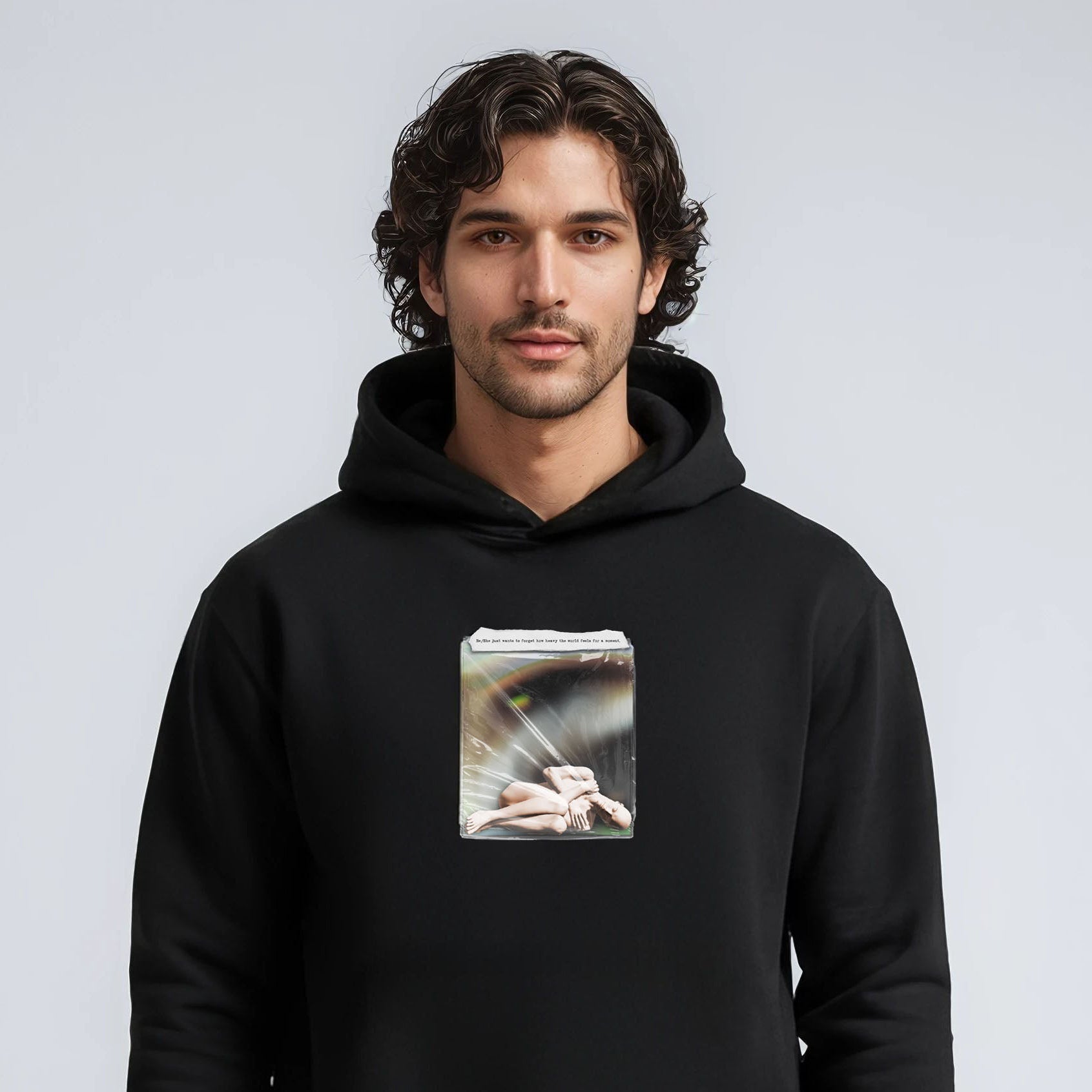 Man wearing a black hoodie with a graphic design on a light gray background