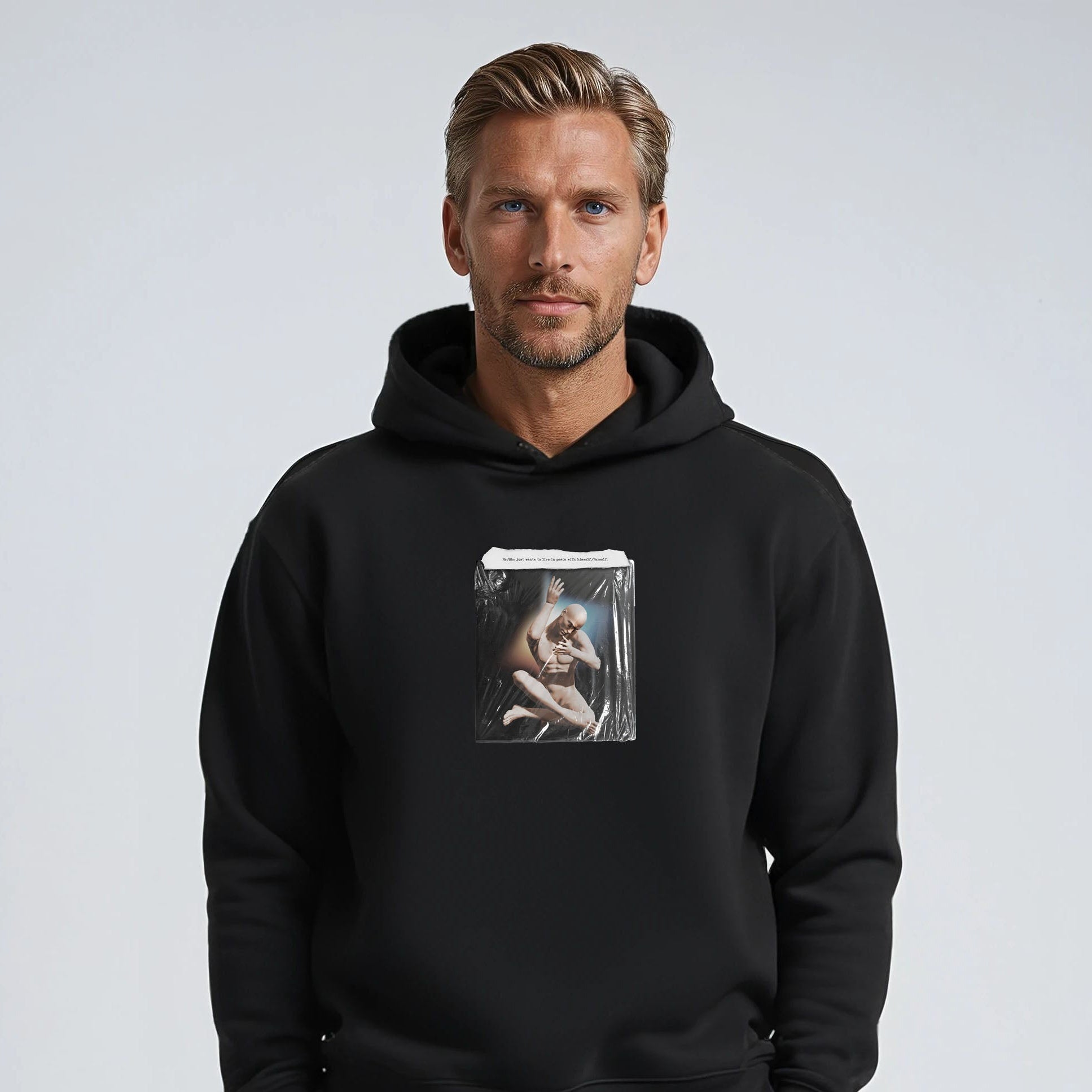 Man wearing a black hoodie with a graphic design on a plain background