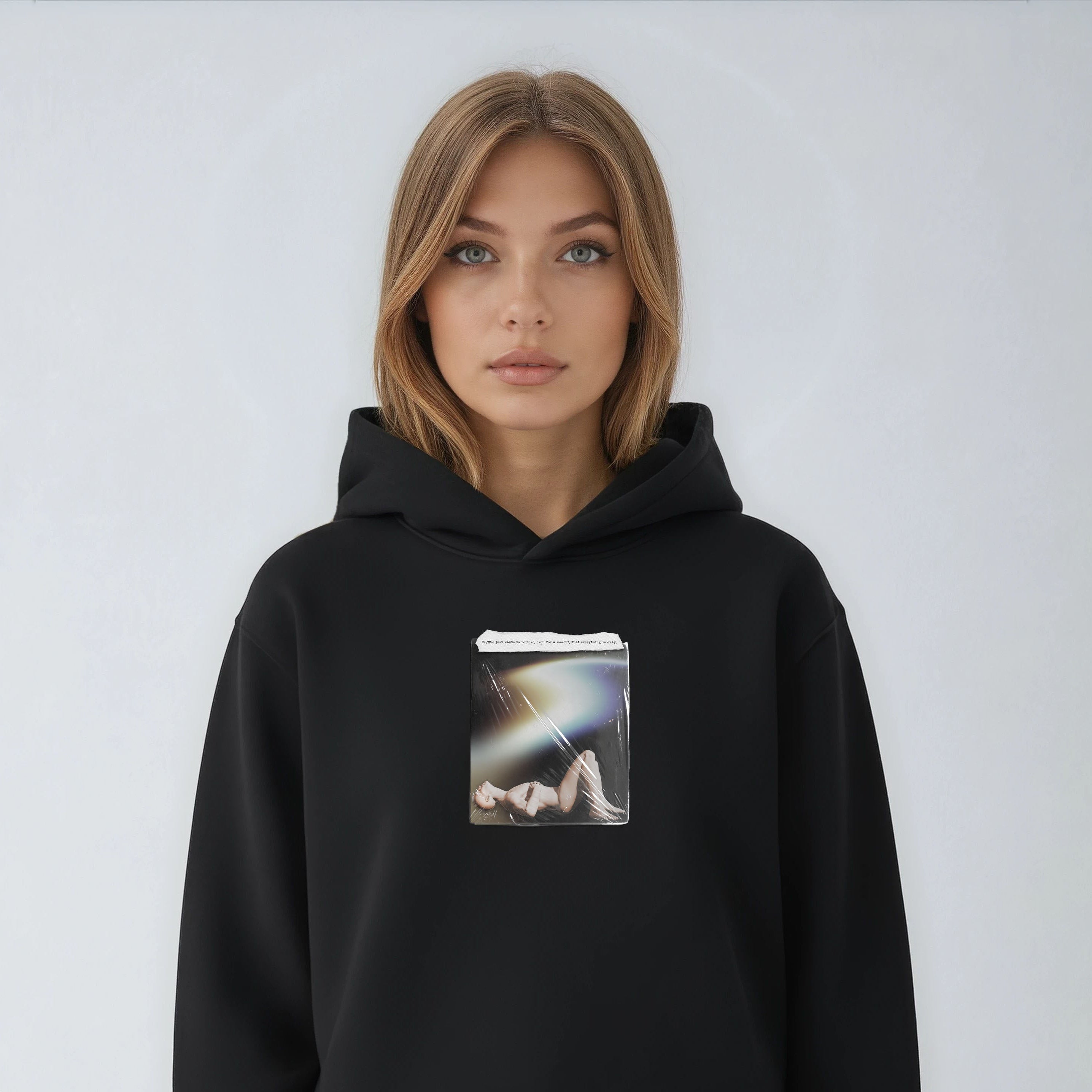 Person wearing a black hoodie with a graphic design on a plain background