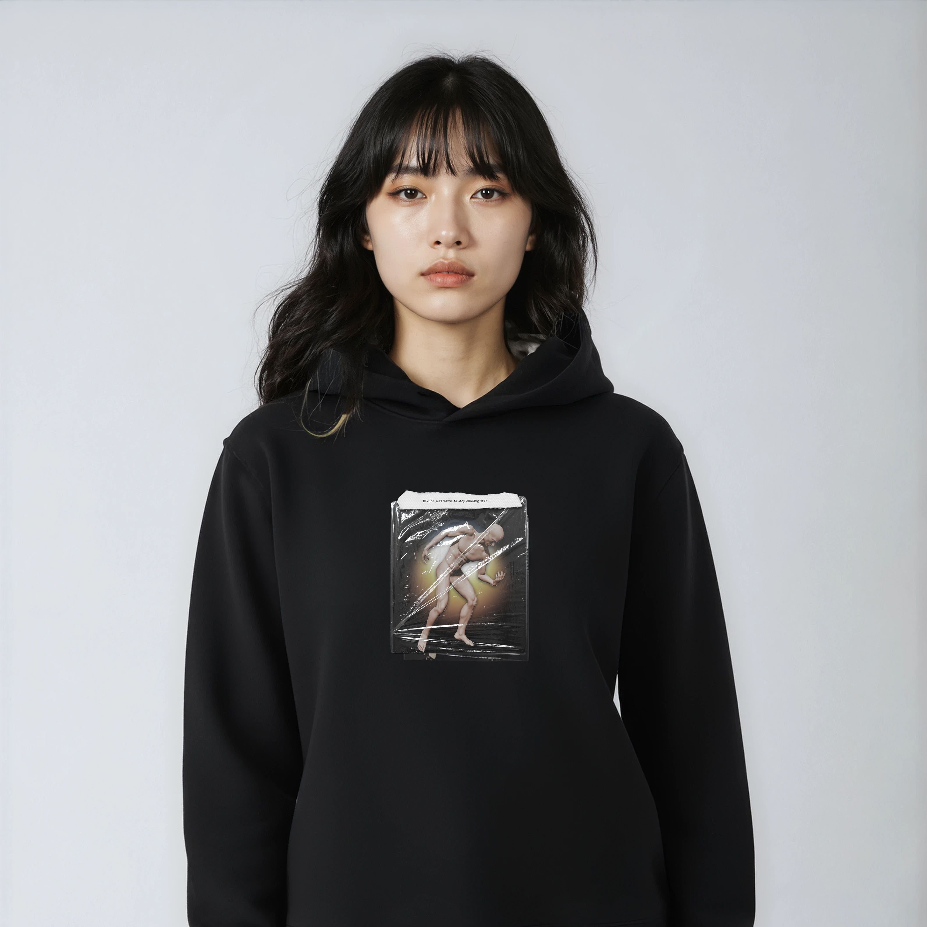 Person wearing a black hoodie with a graphic design on a plain background