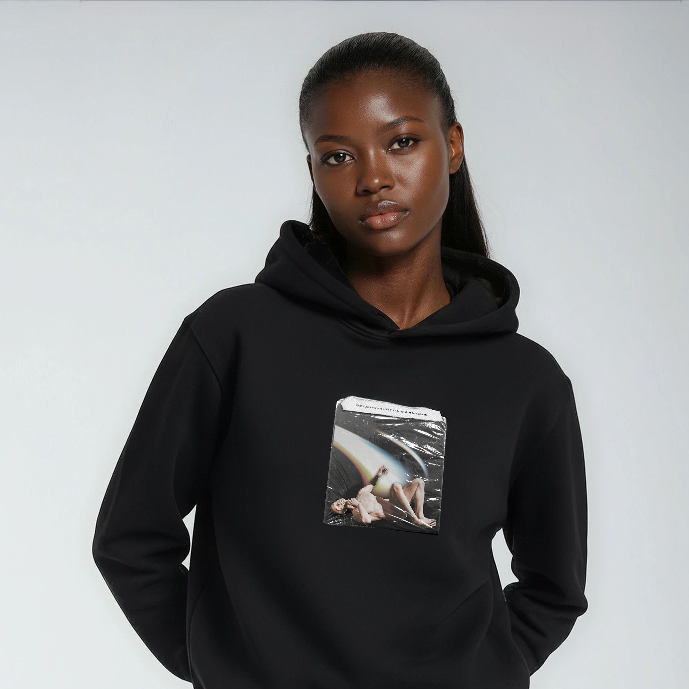 Person wearing a black hoodie with a graphic design on a plain background